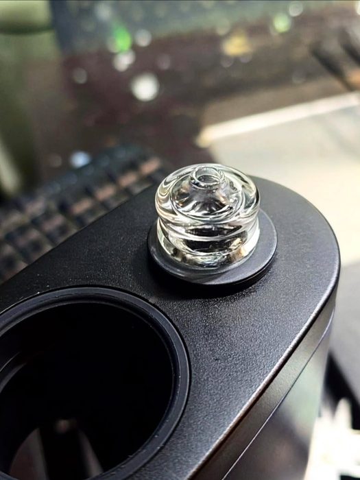 Coopers Glass clear spinner cap seated on a Switch 2: a stepped clear glass cap sitting in the black magnetic ring