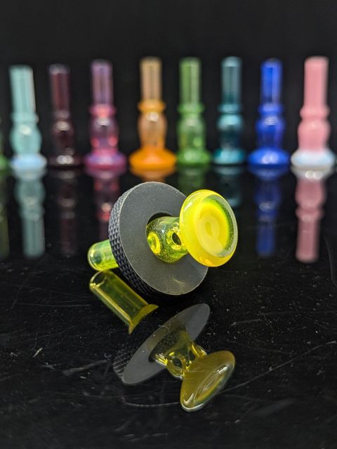 Major Glass Lab joystick: a bright yellow disc-topped glass cap seated in the black knurled magnetic ring, with a row of colored stems in the background